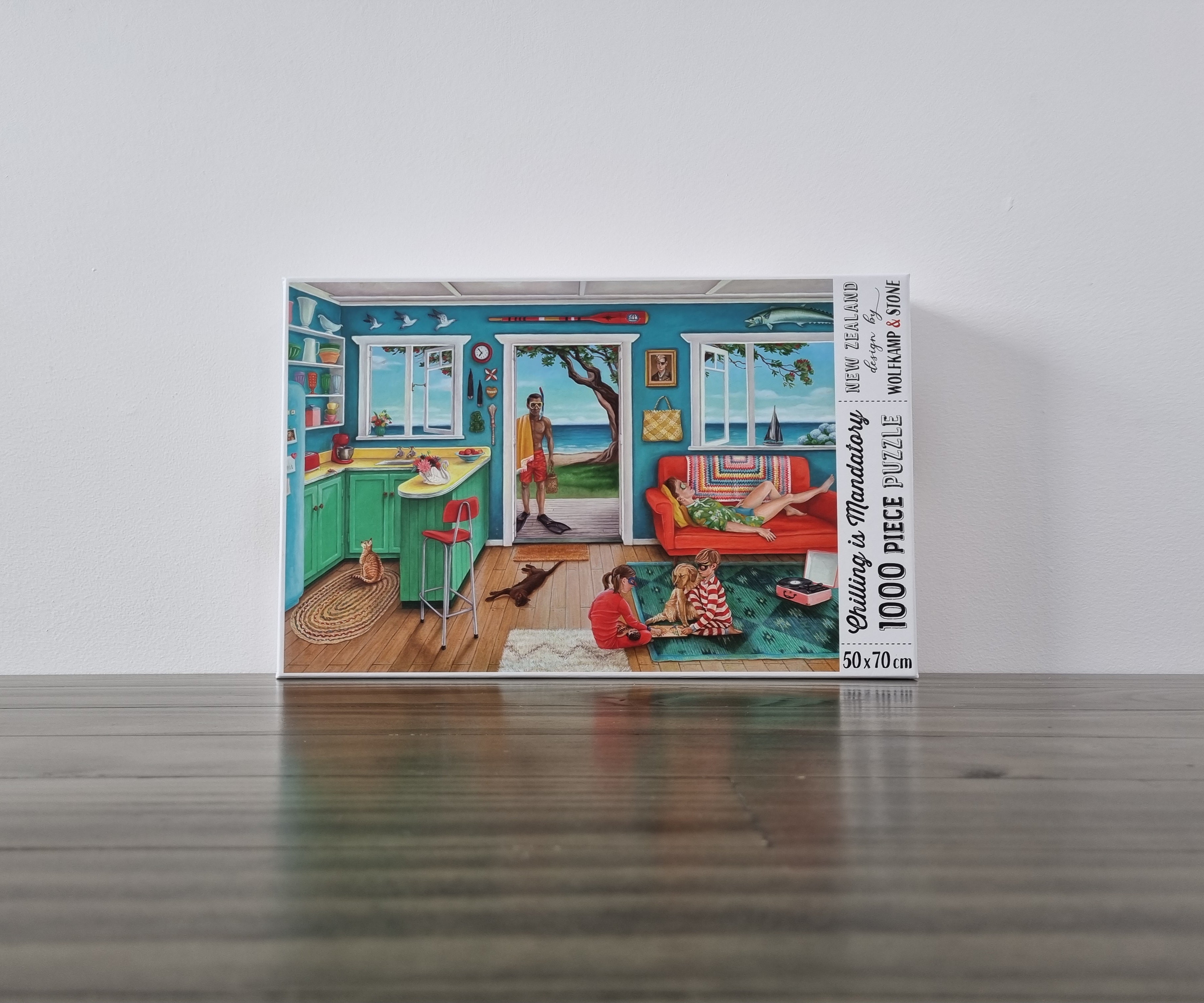 A colourful 1000 piece puzzle depicting a kiwi classic summer holiday image of a beachfront batch, with a family relaxing and playing. Designed in New Zealand by wolfkamp and stone.