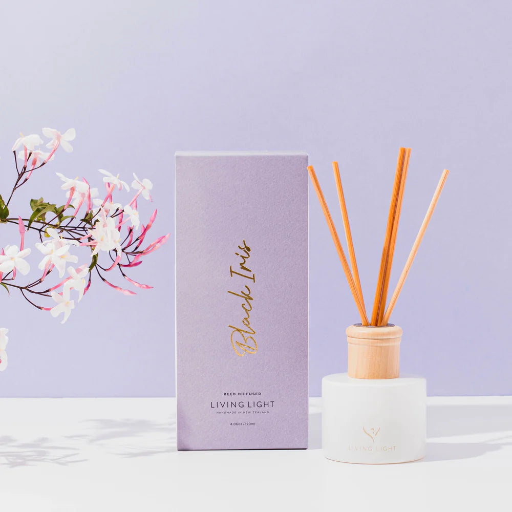 A black iris scented reed diffuser presented in a white glass bottle with natural wooden cap, which comes in an iris purple coloured box. Made in New Zealand by Living Light.