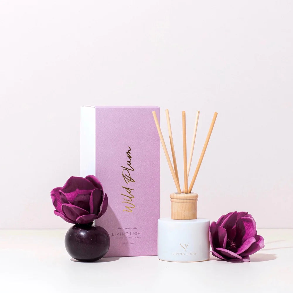A wild plum scented reed diffuser presented in a white glass bottle with natural wooden cap, which comes in a lilac coloured box. Made in New Zealand by Living Light.