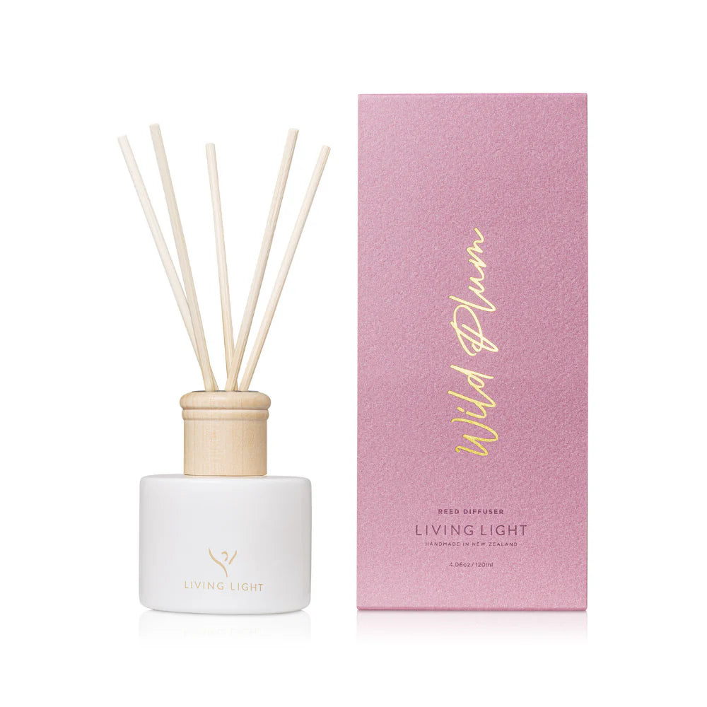 A wild plum scented reed diffuser made by Living Light in New Zealand, presented in a white glass bottle with natural wooden cap, which comes in a lilac coloured box. 